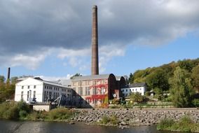 old industrial buildings with chimneys at river, germany, ruhr valley