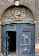 old doorway with lettering and carved figures atop door, denmark, copenhagen