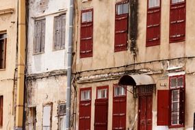 old facade with red shutters at windows, greece