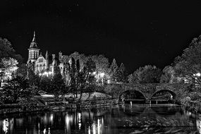 church at river and bridge above water at night