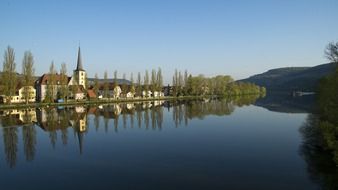 houses and church mirroring on water at spring countryside