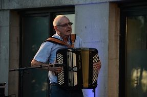 mature man playing accordion, street musician