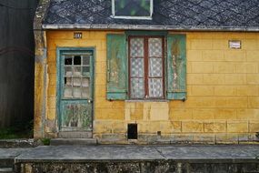 weathered yellow facade of one-storey house,france, picardy