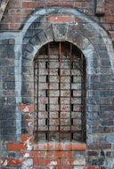 arched window with grid on old bricks wall