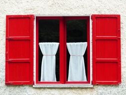 window with red wooden shutters and white curtains