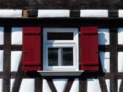 window with red shutters on truss facade