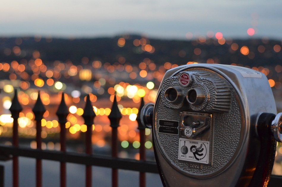 spy glas at forged fence above city lights