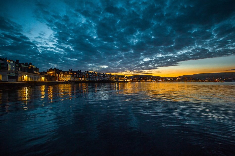 town on coast at dusk under dark blue cloudy sky