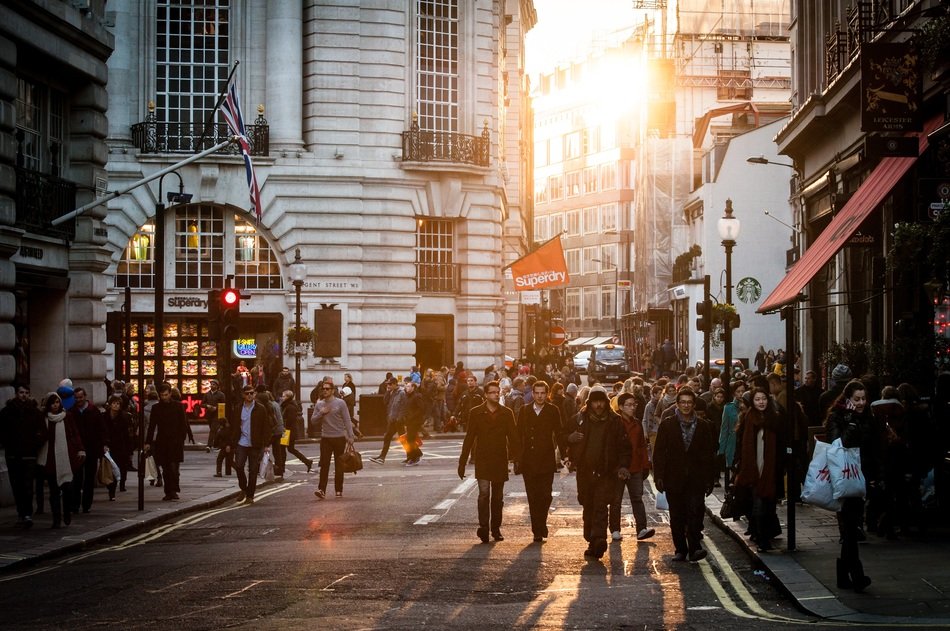 crowd of people on stret in old city at winter sunset, uk, england