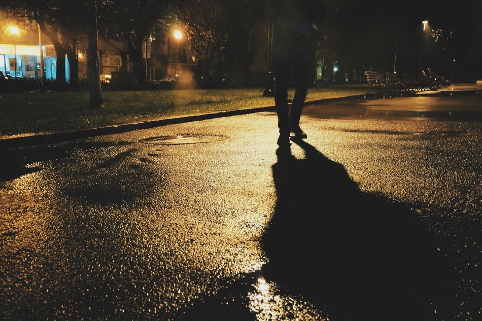 shadow of pedestrian on wet road at night light