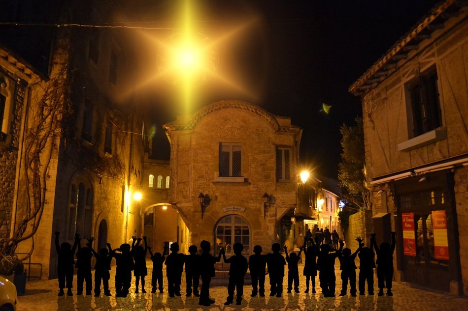 children’s silhouettes in row on square in old town at night