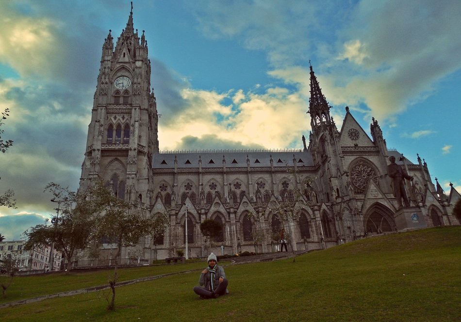 young man sits on grass at Basilica del Voto Nacional, Ecuador, Quito