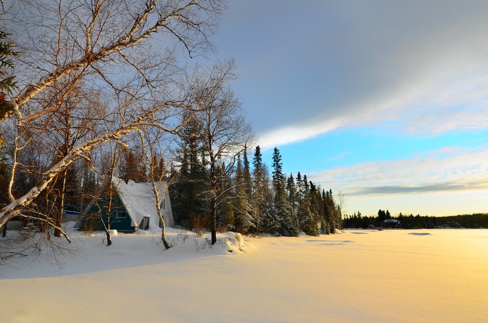 snowy winter landscape with birch and hut at frozen lake