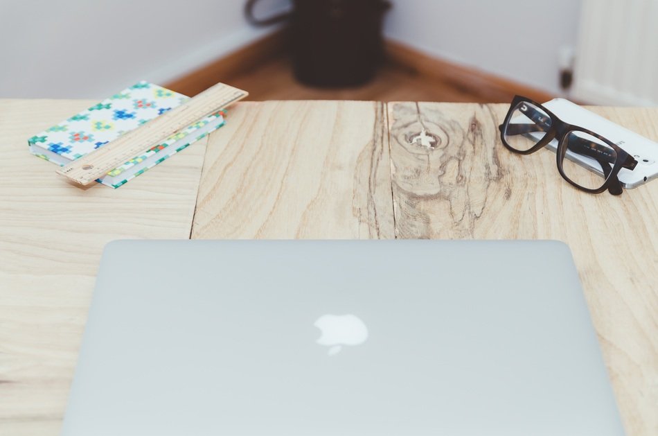 apple laptop and glasses on desk