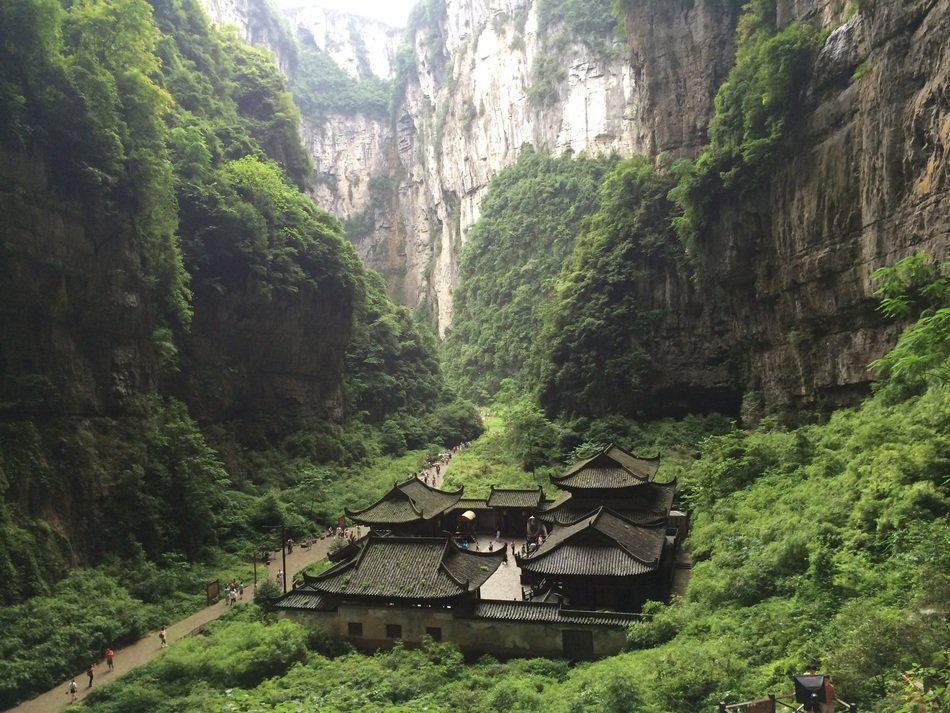 people on path and old buddhist buildings in green canyon