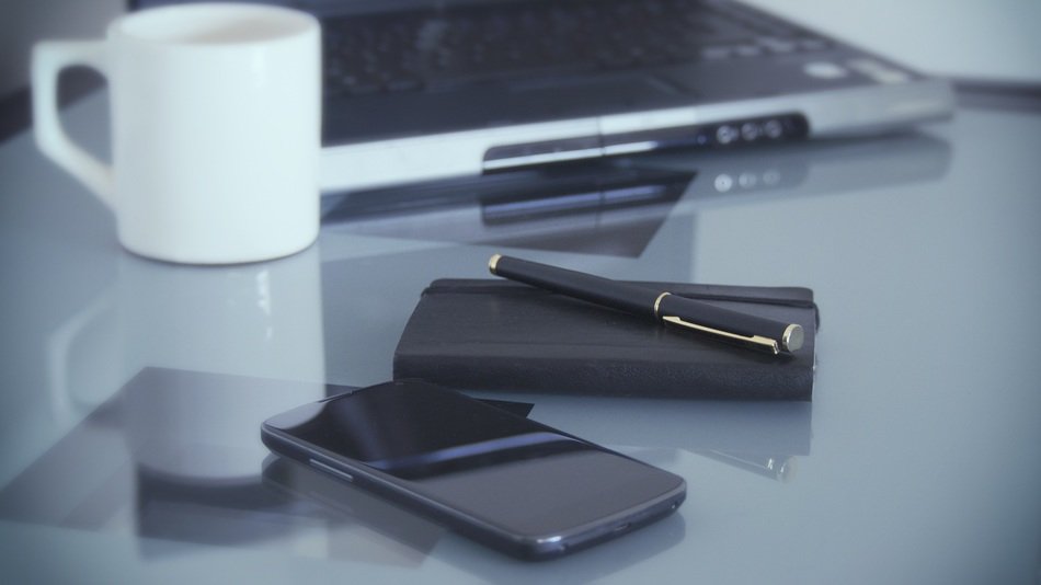 smartphone and white cup on the desktop close-up on blurred background