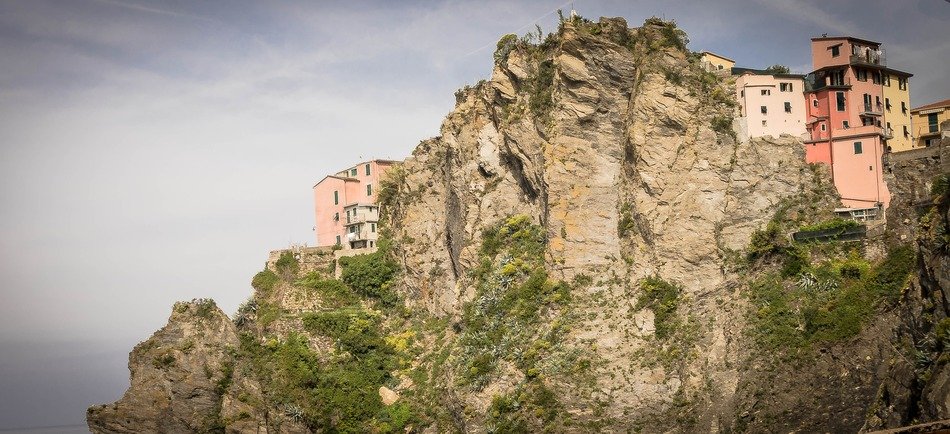 pink houses on cliff at cloudy sky, italy, cinque terre