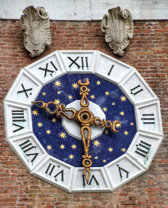 old clock with golden stars on brick wall