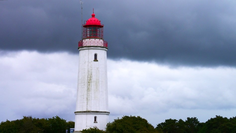 high lighthouse with red top at grey clouds