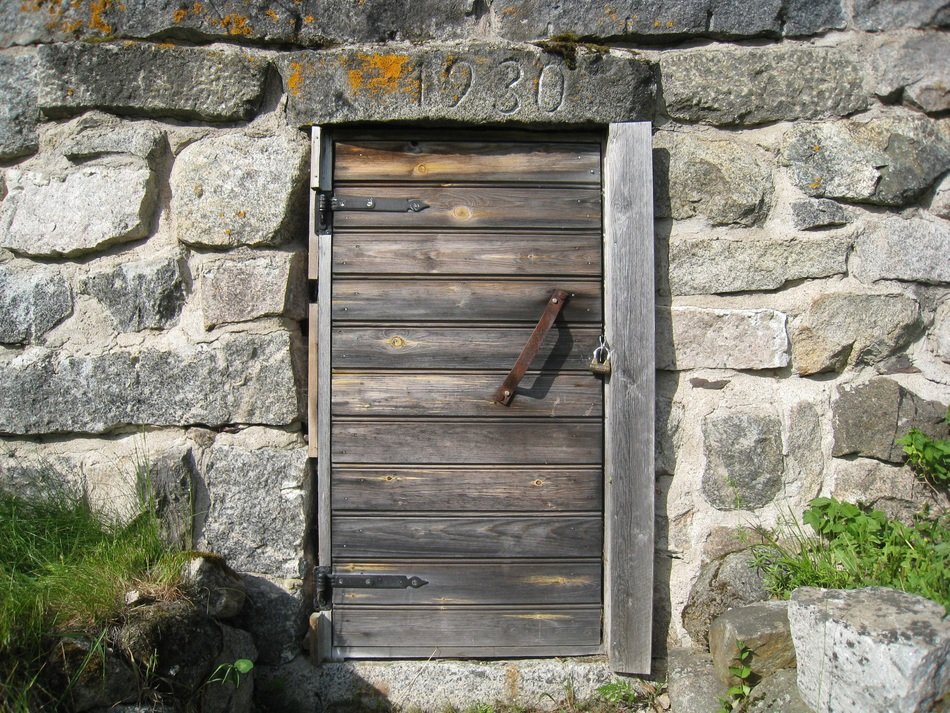 weathered wooden door with rusty handle in stone wall