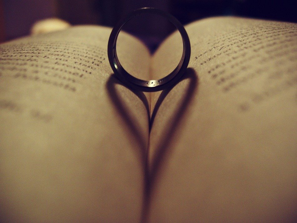 heart form shadow of ring on open book