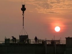 People at the construction site at sunset