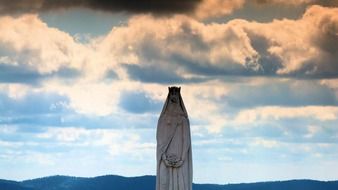 woman with flowers statue at clouds, back light