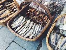 dried and smoked fish in baskets on pavement close-up