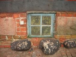 stones on pavement at window of old house