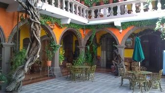 free tables with chairs at arched facade of hotel