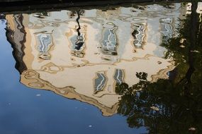 mirroring of old beige building on water