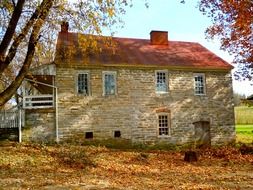 old stone house with red roof at fall, usa, pennsylvania, schaefferstown