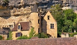 medieval building with tower at rock, france, dordogne