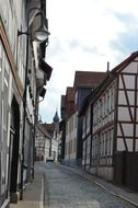 alley with truss buildings and church in old town, germany, goslar