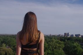 back view of long haired girl looking at city