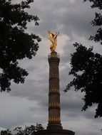 victory column at clouds among trees, germany, berlin
