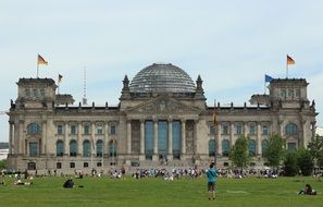 people resting on lawn at bundestag building, germany, berlin