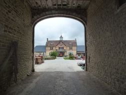 view of old truss business building through arched stone tunnel, france