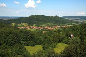 beautiful summer landscape, village at mountain behind forest