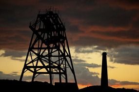 drilling tower and industrial chimney at sunset sky