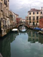 boats on channel at bridge in city, italy, venice