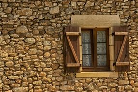 wooden window with shutters in old stone wall, france