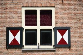 traditional painted shutters at window on brick wall, netherlands