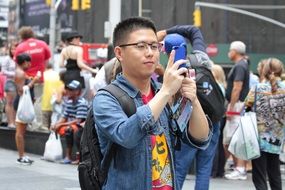 asian boy taking selfie with phone on street, usa, manhattan, new york city