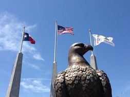 eagle sculpture and flags at blue sky, usa, texas