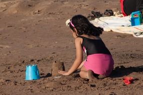 child girl plays on sand beach