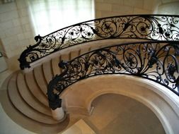 beautiful curwed staircase with wrought iron railing in interior, france, paris