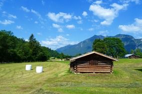hay balls and log building on meadow at mountains, germany, bavaria
