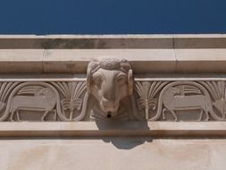 animal head, aged stone sculpture on facade