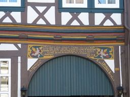 shield with angls and golden lettering at top of gates in aged truss house